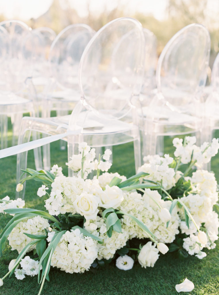 Clear wedding ceremony chairs with flowers