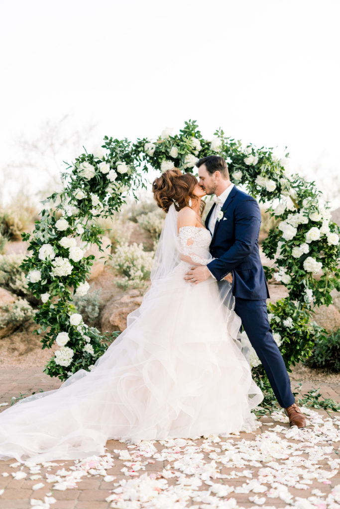 Bride and groom kissing in front of arch Arizona wedding